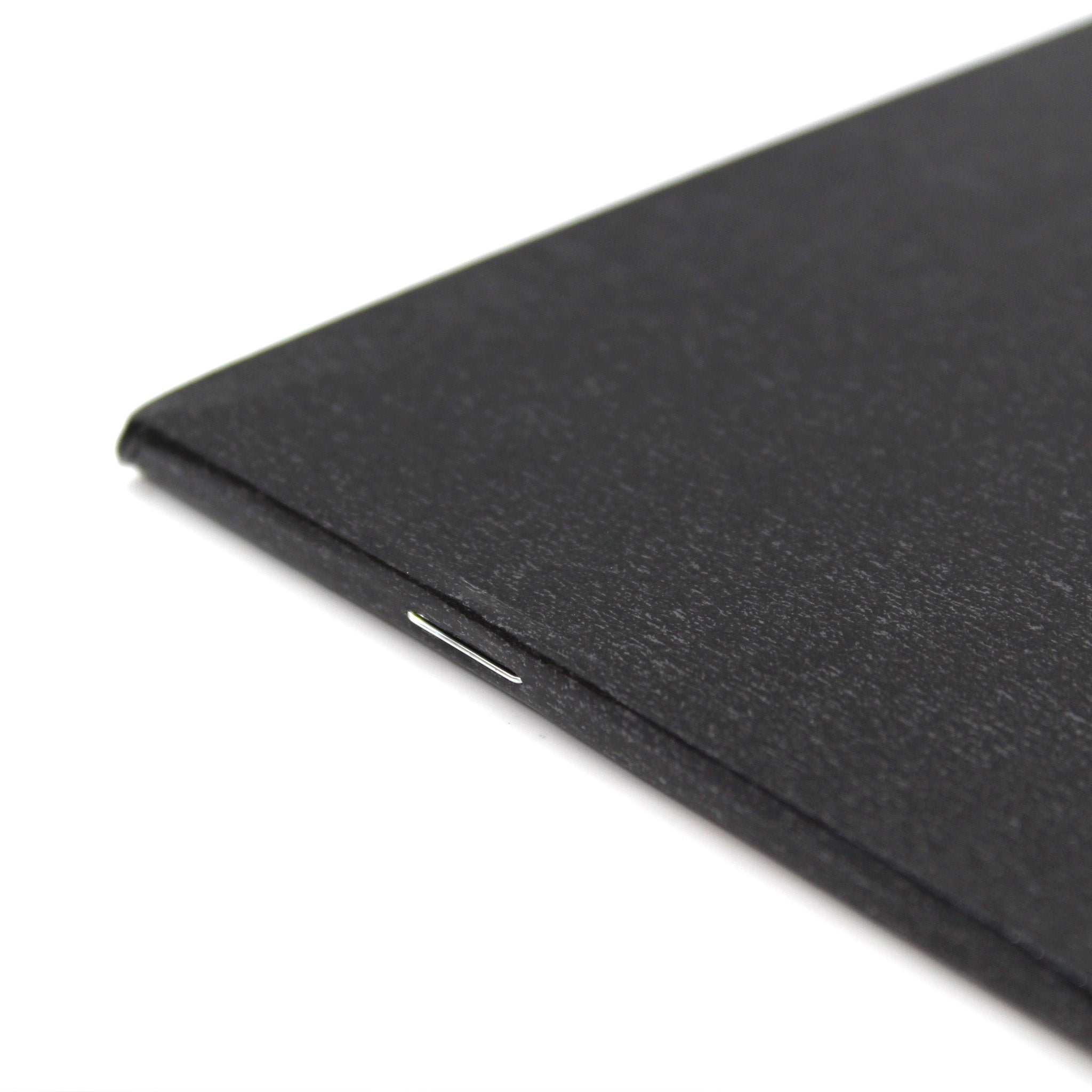 Close Up Of Staple Binding On A5 Silvine Field Black Sketchbook 140gsm Paper On A White Background