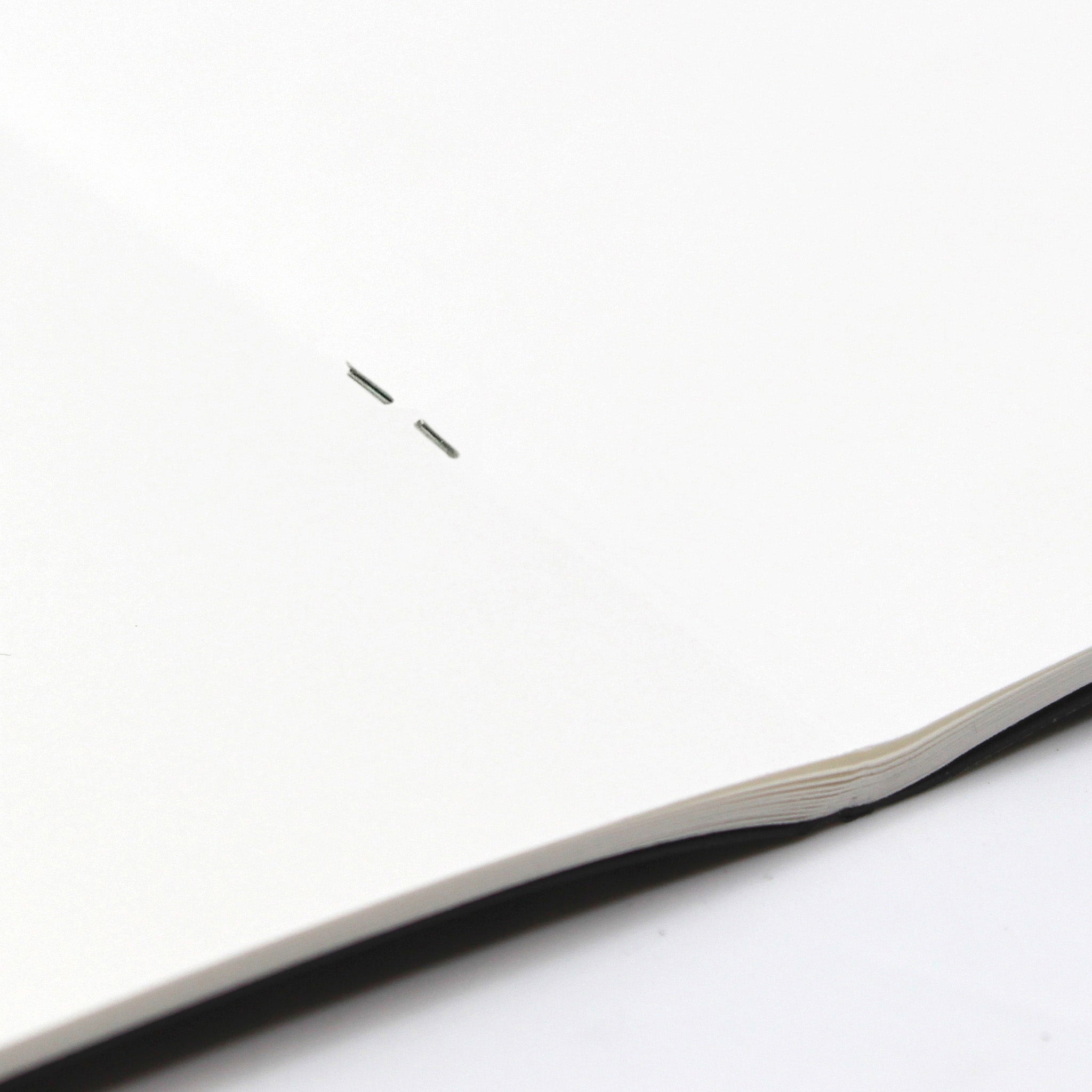 Close Up Of Binding On A Open A5 Silvine Field Black Sketchbook 140gsm Paper On A White Background