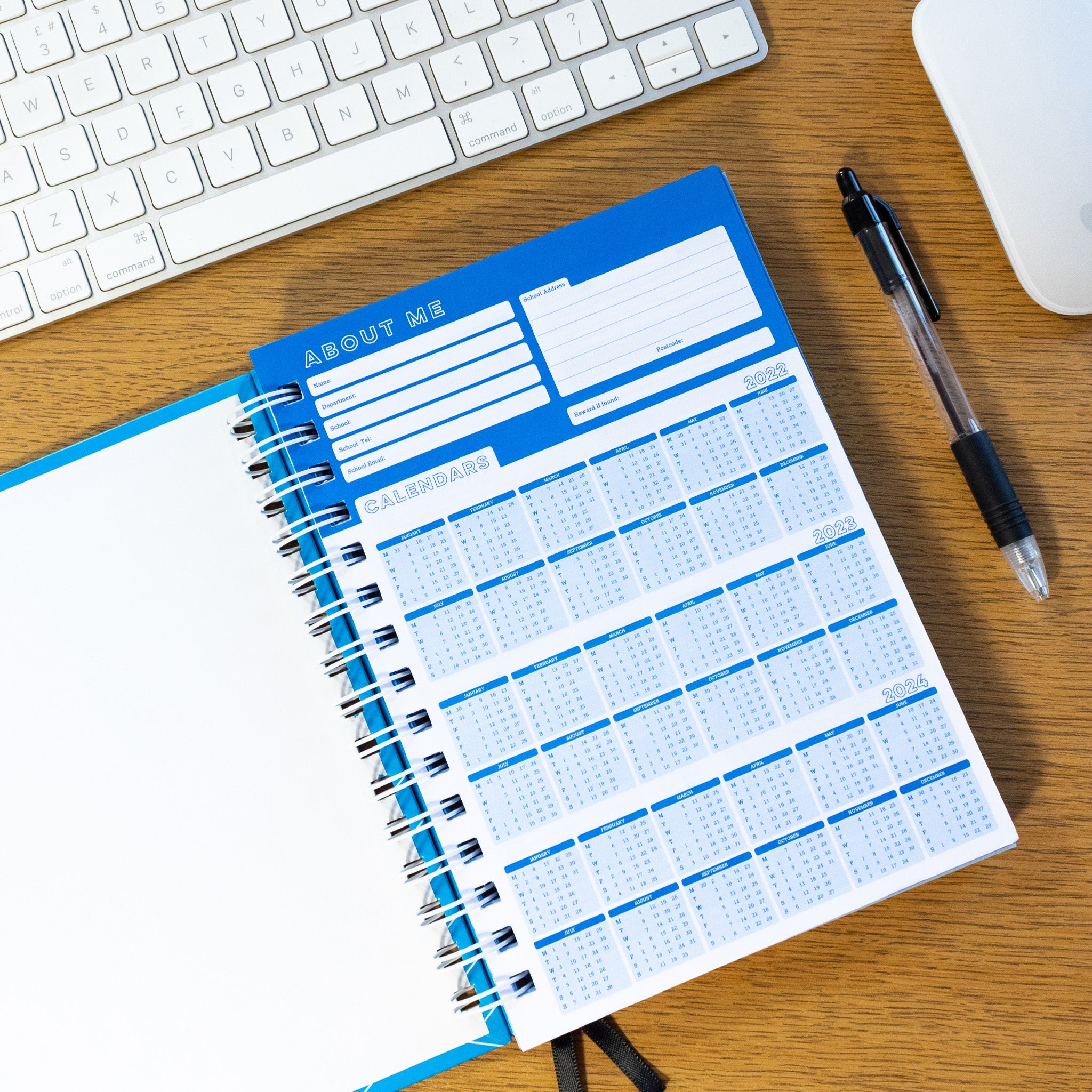 6 Period Teacher Planner Ringbound Book Open On A Desk, With A Keyboard, Mouse & Pen.