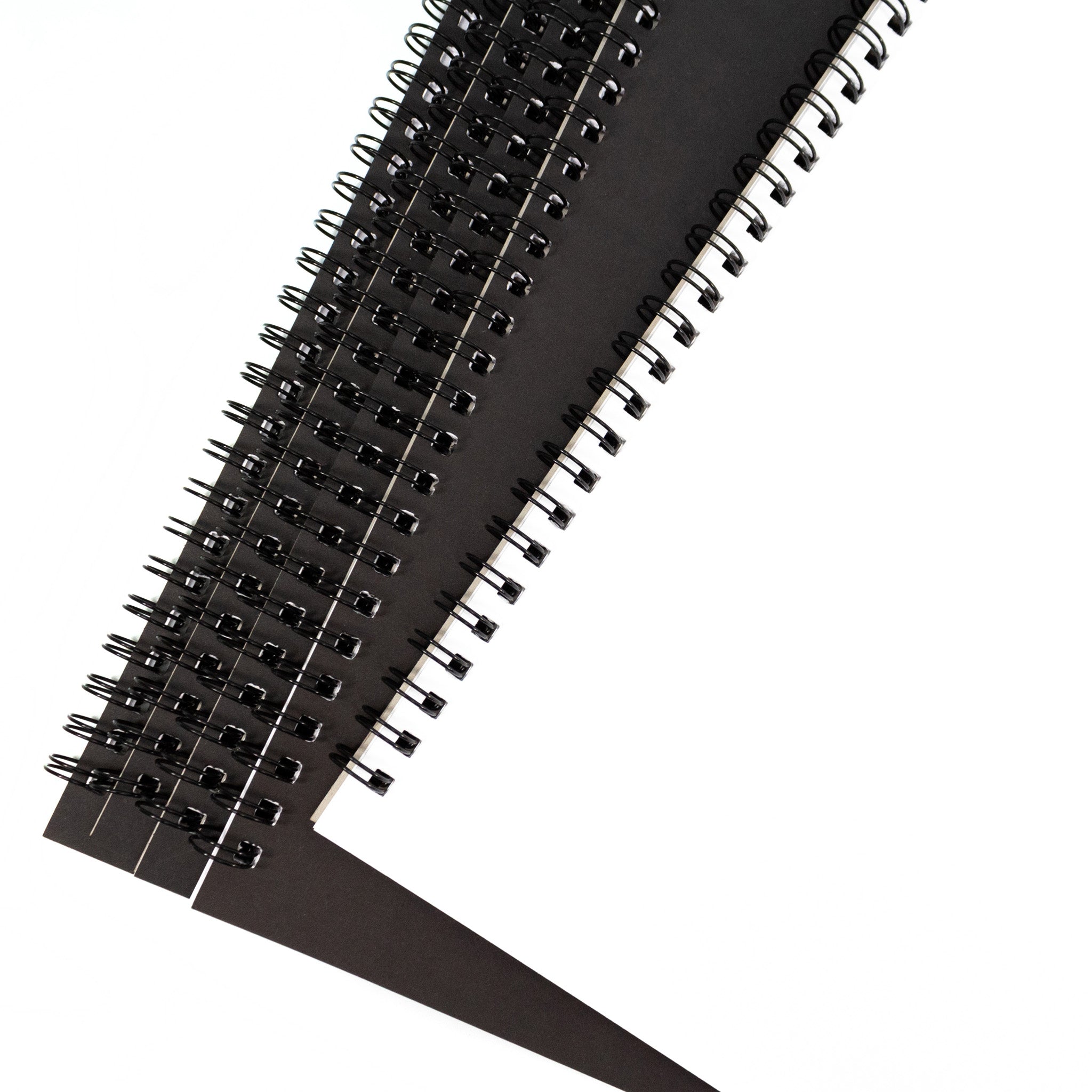 Close Up Of Black Spiral-Bound Classroom Floor Sketchbooks Piled Up On A White Background